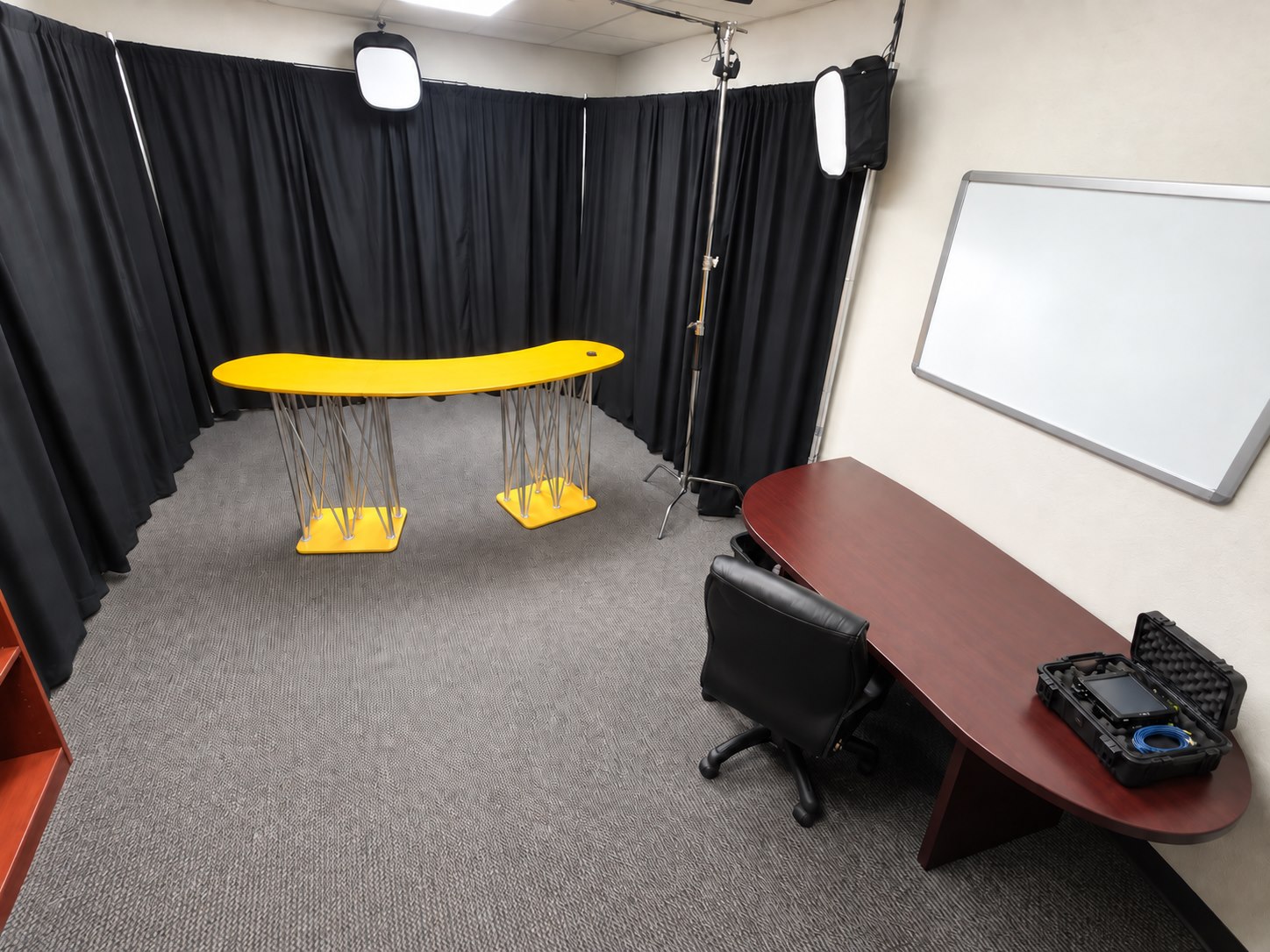 Presentation Studio with a curved yellow presenter desk, black backdrop and studio lights